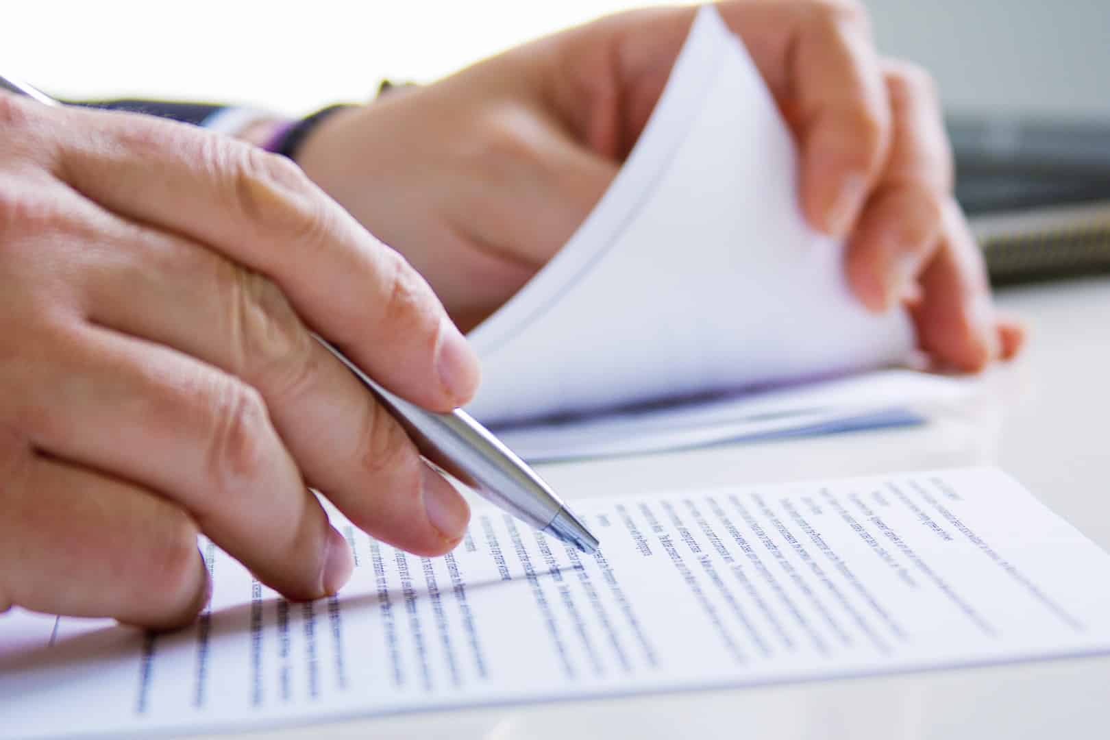 Ręce osoby analizującej dokumenty – udział pokrzywdzonego w postępowaniu karnym według kancelarii Janusza Stefańczyka