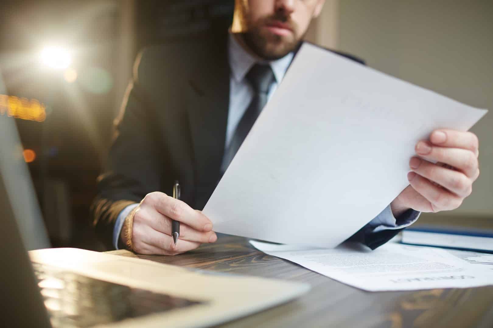 Mężczyzna w garniturze analizujący dokument z umową – symboliczne przedstawienie kary umownej